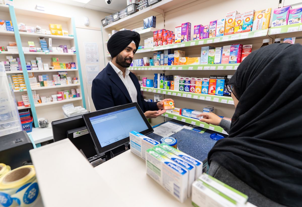 A MediPill pharmacist handing a prescription over the counter
